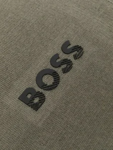 Iškili, tekstūrinė „embossed“ stiliaus spauda ant tamsiai žalio tekstilės gaminio.