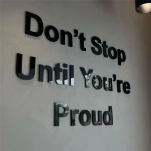 Lazeriu pjautos juodo blizgaus organinio stiklo 3D raidės su stipriu klijų sluoksniu, formuojančios motyvacinį užrašą ant sienos verslo interjere.