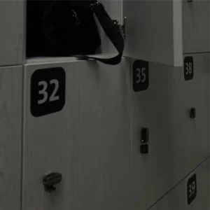 Profesionali lipdukų gamyba verslui: ploteriu pjauti ilgaamžiai vinilo lipdukai spintelių numeracijai, užklijuoti ant pilkų persirengimo kambario baldų.